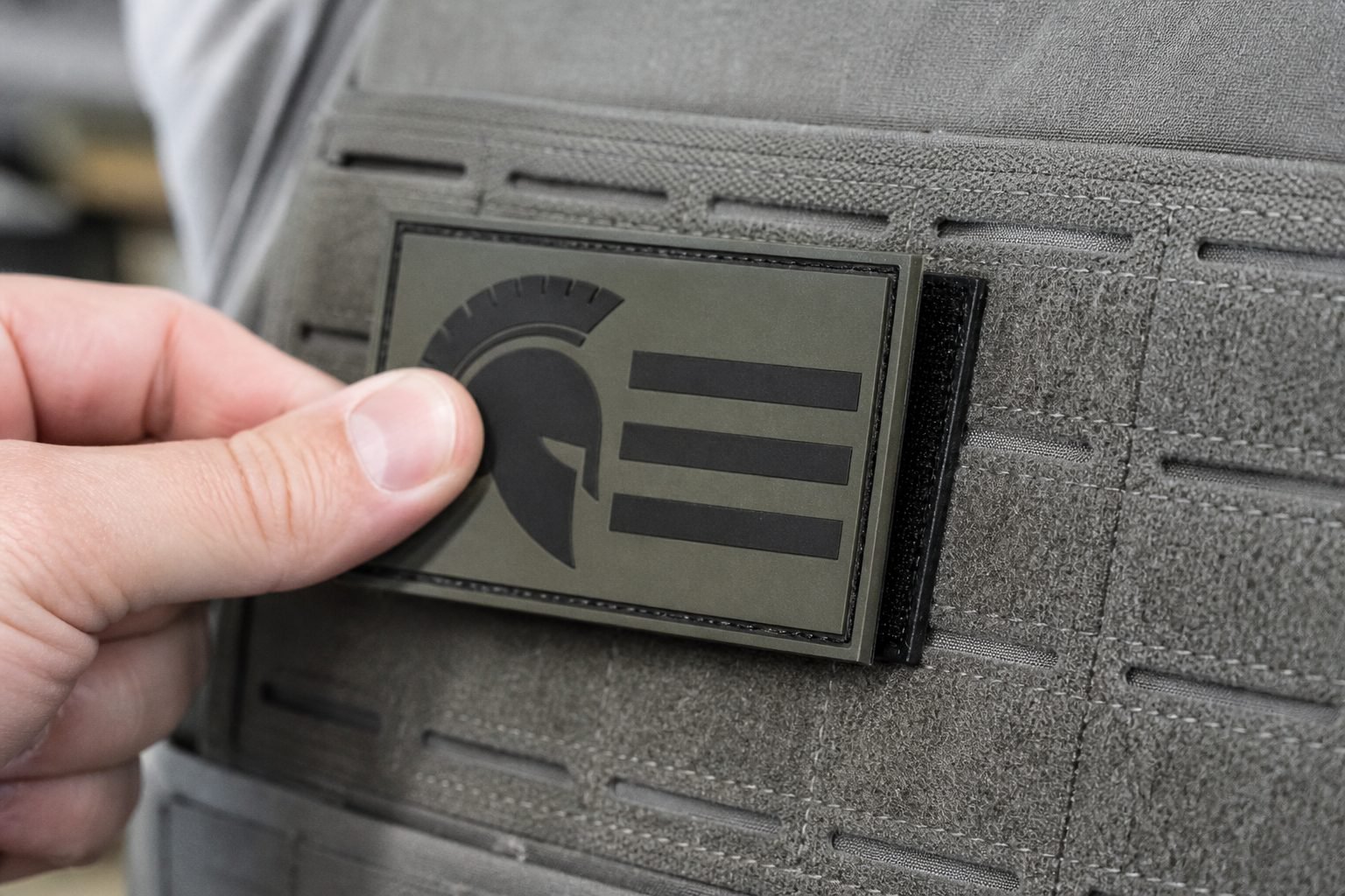 Hook-backed morale patch being pressed onto a loop panel on a vest